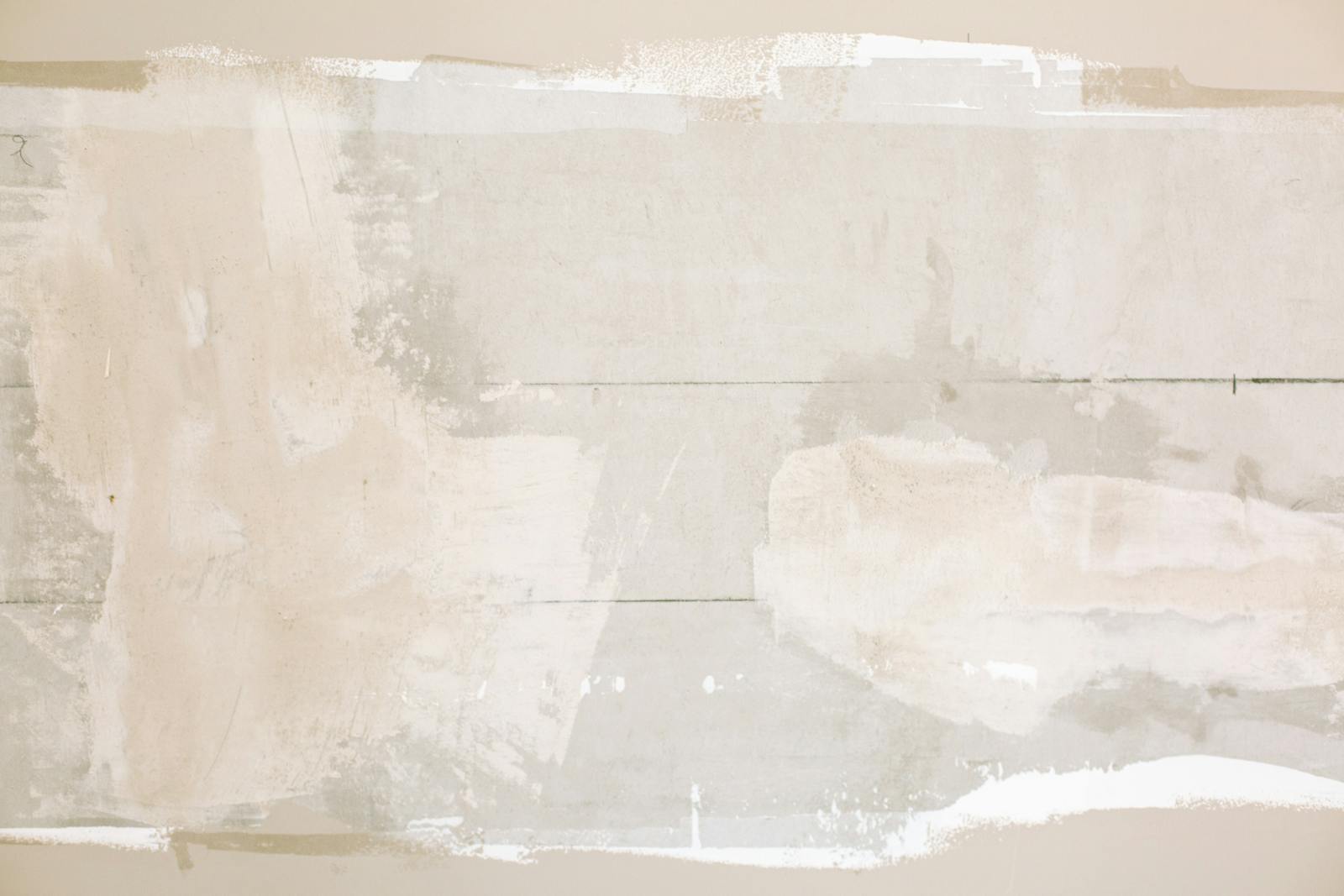 Close-up of an unfinished wall showing plaster and paint textures in a home renovation.